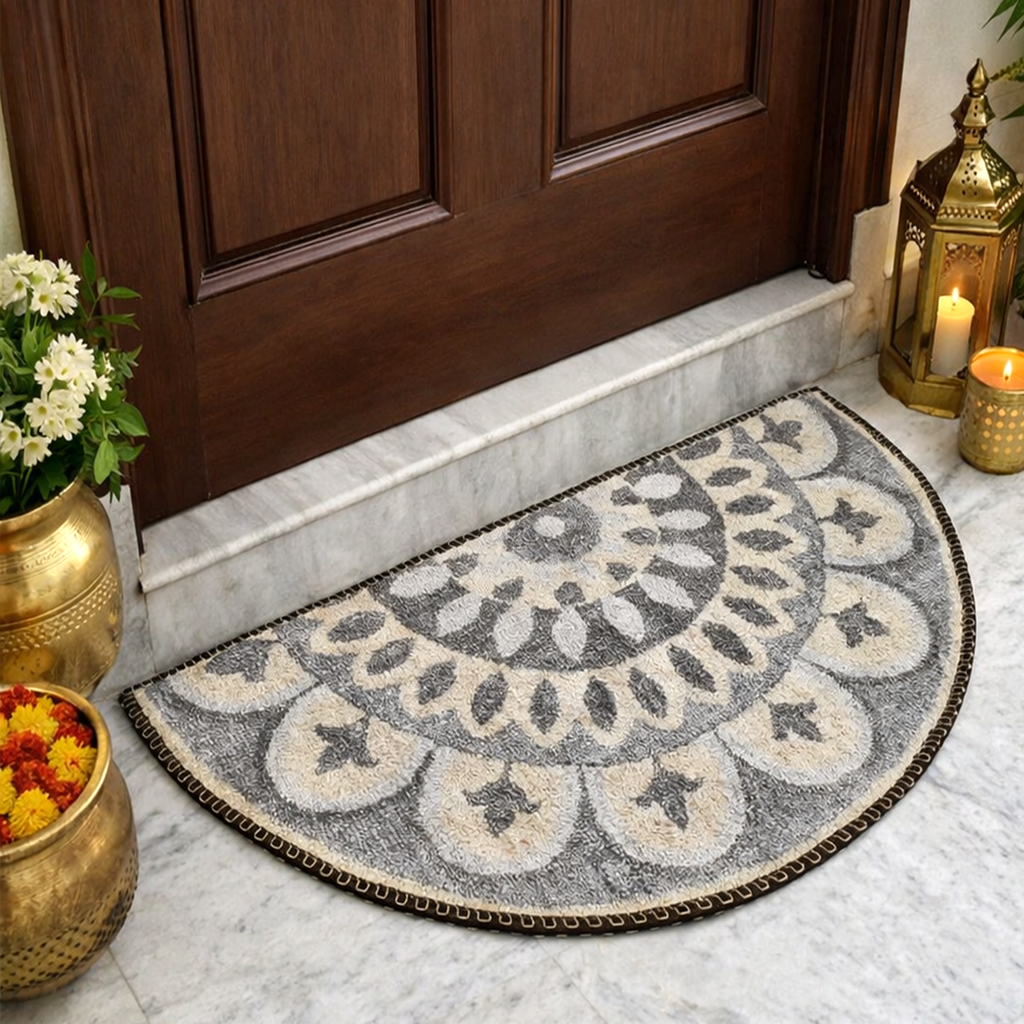 Decorative doormat with floral pattern on a marble floor in front of a wooden door.